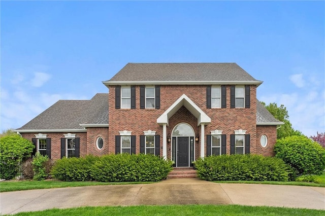 colonial-style house with a shingled roof and brick siding