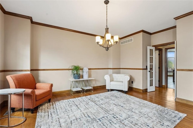 sitting room featuring crown molding, baseboards, a notable chandelier, and wood finished floors