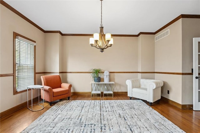 sitting room featuring visible vents, crown molding, wood finished floors, baseboards, and a chandelier