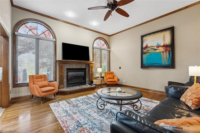 living area with baseboards, a ceiling fan, wood finished floors, and ornamental molding