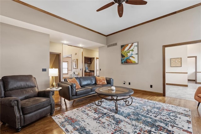 living area with visible vents, crown molding, wood finished floors, and ceiling fan