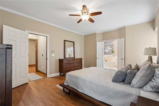 bedroom with a ceiling fan, crown molding, wood finished floors, baseboards, and ensuite bath
