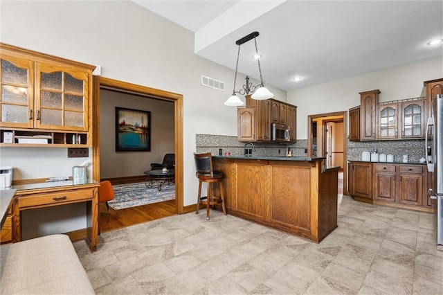 kitchen featuring visible vents, a peninsula, glass insert cabinets, tasteful backsplash, and appliances with stainless steel finishes