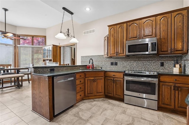 kitchen featuring visible vents, a peninsula, tasteful backsplash, a sink, and stainless steel appliances