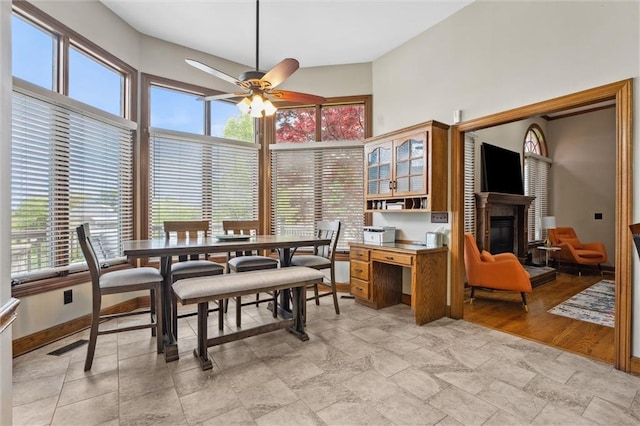 dining space with a glass covered fireplace, ceiling fan, and a wealth of natural light