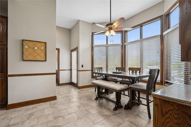 dining space with baseboards, a high ceiling, and a ceiling fan