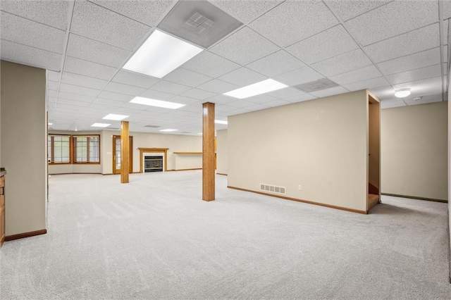 basement with carpet floors, visible vents, and a drop ceiling