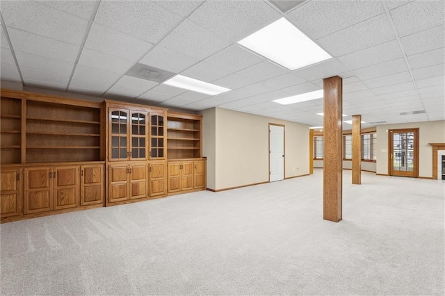 basement with baseboards, a drop ceiling, and light colored carpet