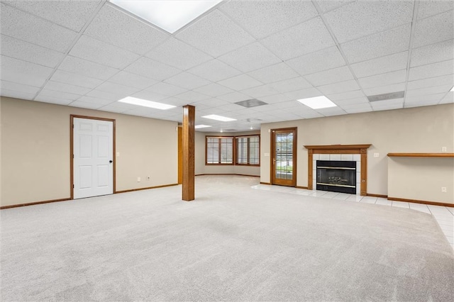 basement featuring baseboards, a drop ceiling, and carpet flooring