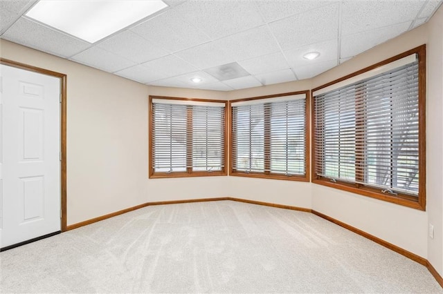 carpeted empty room featuring baseboards and a paneled ceiling