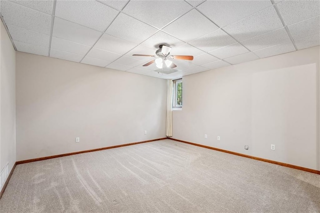 carpeted empty room featuring baseboards, ceiling fan, and a drop ceiling