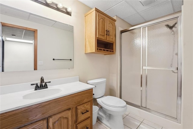 bathroom featuring tile patterned flooring, vanity, toilet, a paneled ceiling, and a stall shower