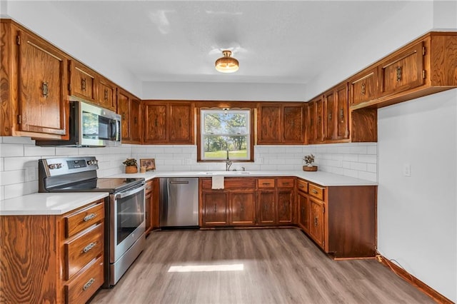 kitchen with appliances with stainless steel finishes, light wood-style floors, and brown cabinetry