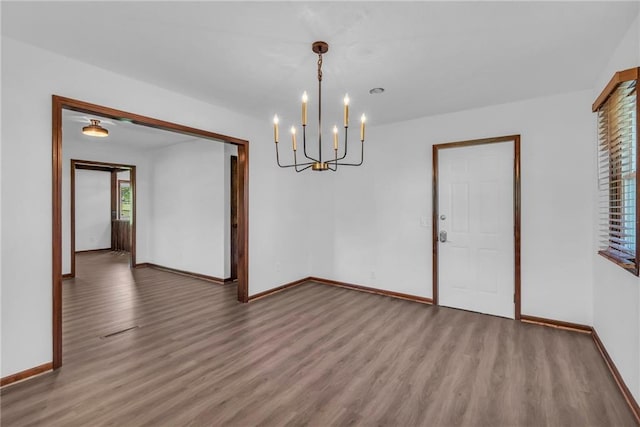 unfurnished dining area featuring a chandelier, wood finished floors, and baseboards