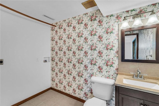bathroom with vanity, wallpapered walls, baseboards, toilet, and tile patterned flooring