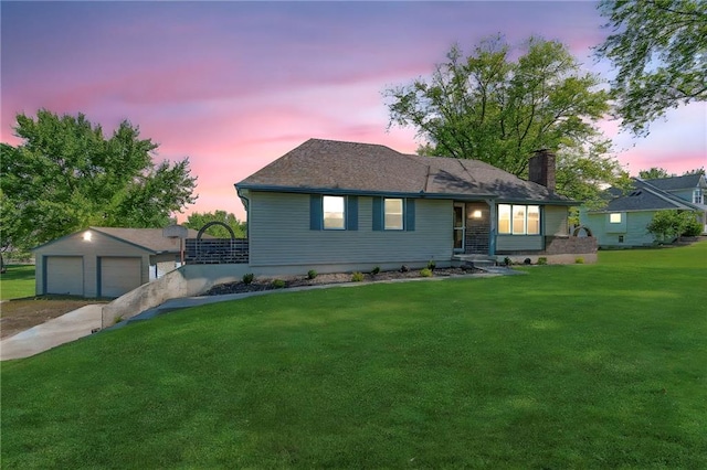 ranch-style home featuring a chimney, a yard, a detached garage, and an outbuilding
