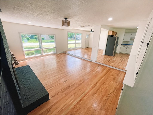 408 W 101st Ter, Kansas City, MO 64114 - unfurnished living room with recessed lighting, a textured ceiling, and light wood-style flooring