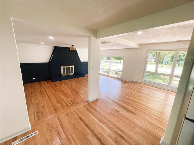 408 W 101st Ter, Kansas City, MO 64114 - unfurnished living room with visible vents, a brick fireplace, wood finished floors, recessed lighting, and a textured ceiling