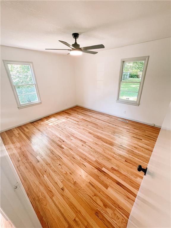 408 W 101st Ter, Kansas City, MO 64114 - unfurnished room featuring a healthy amount of sunlight, ceiling fan, and wood finished floors