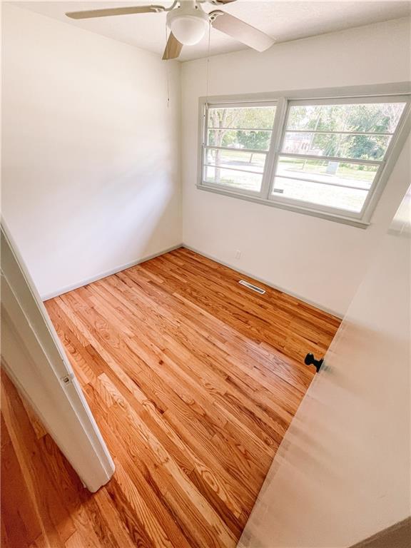 408 W 101st Ter, Kansas City, MO 64114 - spare room with ceiling fan, visible vents, and wood finished floors