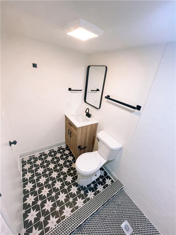 408 W 101st Ter, Kansas City, MO 64114 - bathroom featuring vanity, baseboards, tile patterned floors, and toilet