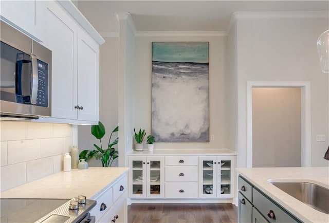 kitchen featuring stainless steel microwave, crown molding, a sink, backsplash, and dark wood-style flooring