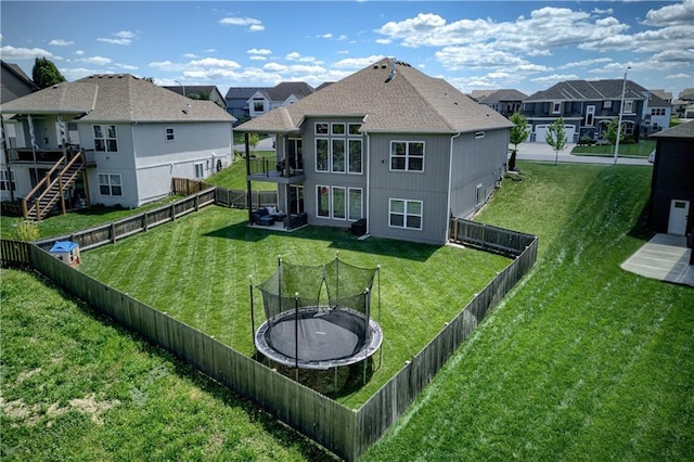 back of property with a residential view, a trampoline, and a balcony