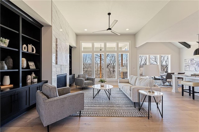 living area featuring a high end fireplace, wood finished floors, and a ceiling fan