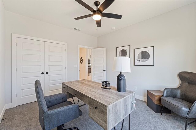 carpeted home office with baseboards, a ceiling fan, and visible vents