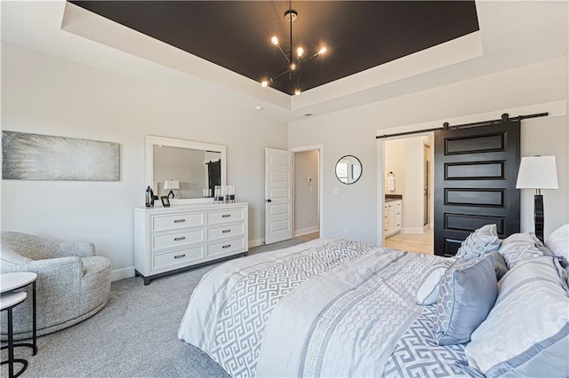bedroom with a barn door, a raised ceiling, light carpet, connected bathroom, and baseboards