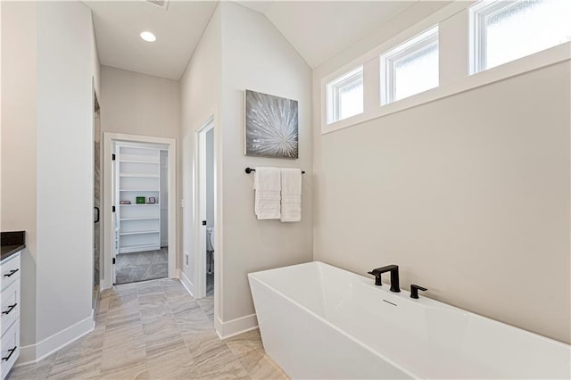 full bathroom with a freestanding tub, baseboards, marble finish floor, and vanity