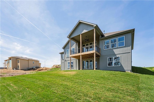 rear view of property with a yard, a balcony, and ceiling fan
