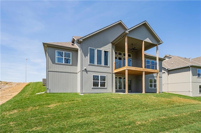 rear view of property featuring ceiling fan, a balcony, and a yard