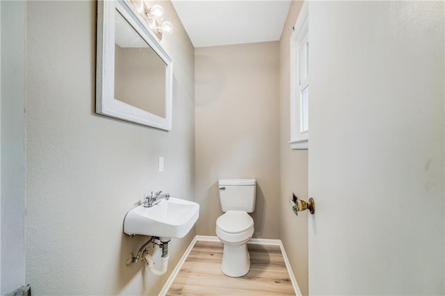 312 W Pine St, Butler, MO 64730 - bathroom featuring toilet, baseboards, wood finished floors, and a sink