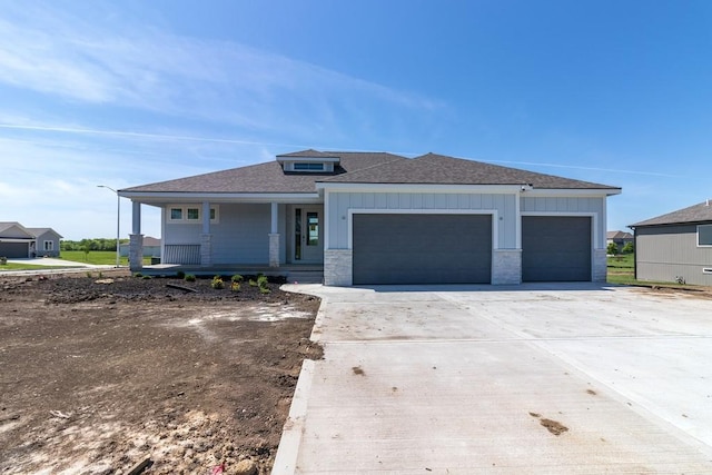 prairie-style home with a garage, board and batten siding, roof with shingles, and a porch