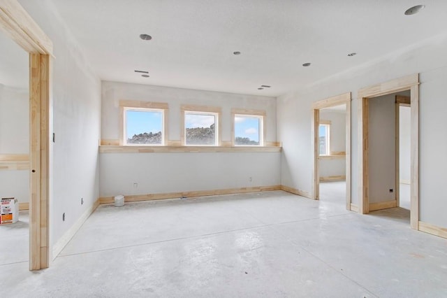 spare room featuring concrete floors and baseboards