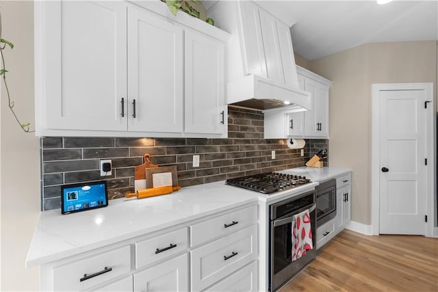 5566 Thousand Oaks Dr, Parkville, MO 64152 - kitchen featuring white cabinetry, decorative backsplash, appliances with stainless steel finishes, light wood-style floors, and custom exhaust hood