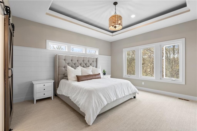 5566 Thousand Oaks Dr, Parkville, MO 64152 - bedroom with a barn door, a raised ceiling, visible vents, light carpet, and baseboards