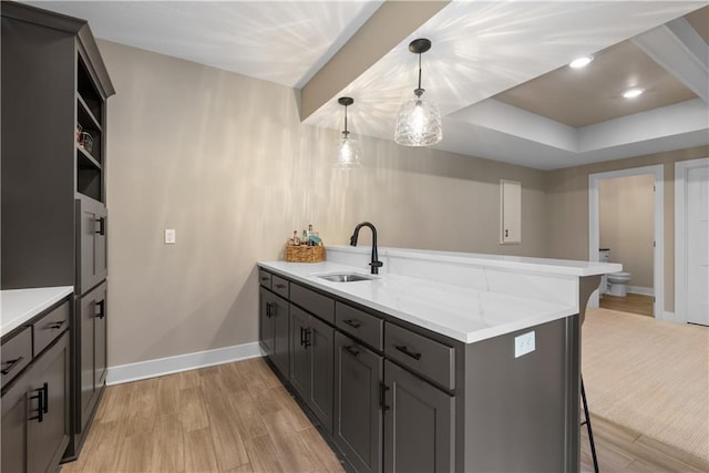 5566 Thousand Oaks Dr, Parkville, MO 64152 - kitchen with a sink, light wood-style floors, a kitchen breakfast bar, a peninsula, and baseboards
