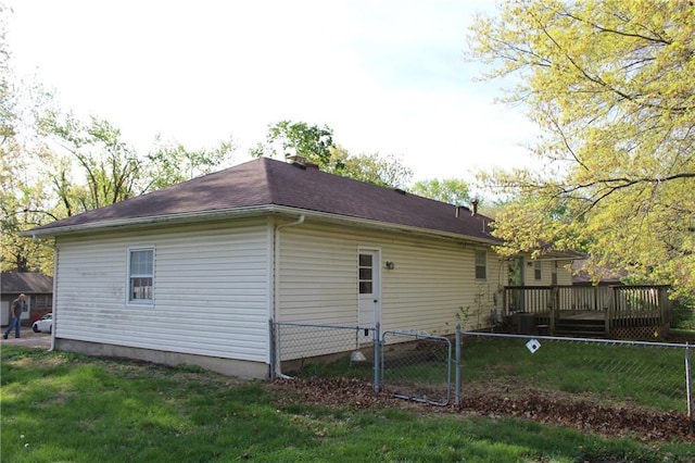 view of side of home featuring a lawn, fence, and a wooden deck