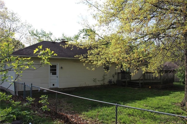 back of house featuring a lawn, a deck, a shingled roof, and a fenced backyard