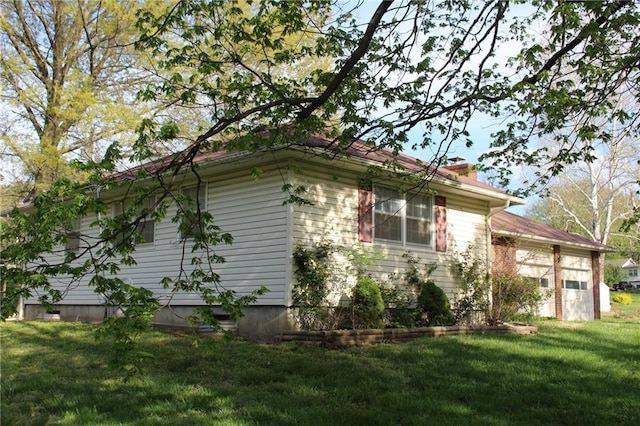 view of side of property with a lawn, a chimney, and a garage
