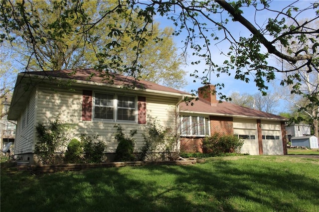 view of front facade with a chimney, an attached garage, and a front lawn
