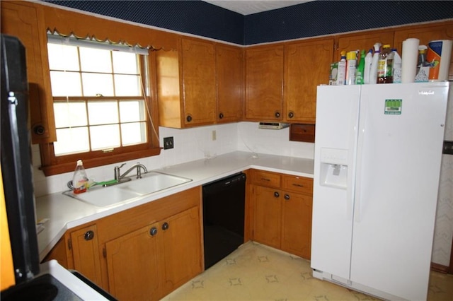 kitchen with brown cabinetry, a sink, light countertops, white fridge with ice dispenser, and black dishwasher