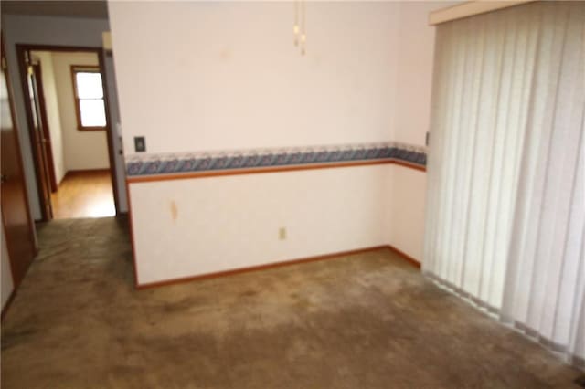 empty room featuring baseboards and dark colored carpet