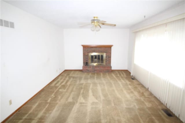 unfurnished living room with a fireplace, carpet, a ceiling fan, and visible vents