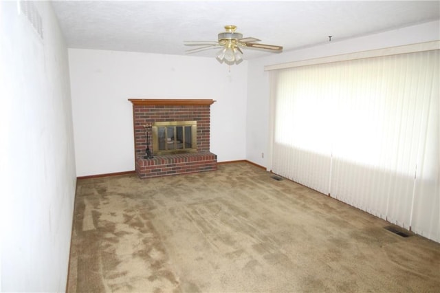 unfurnished living room with visible vents, a ceiling fan, carpet, and a brick fireplace