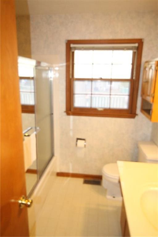 bathroom featuring vanity, a shower stall, toilet, and visible vents