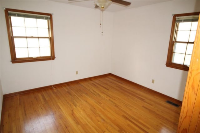 unfurnished room with light wood-style floors, baseboards, a ceiling fan, and visible vents