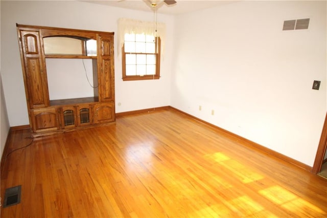 empty room featuring visible vents, light wood-style flooring, and baseboards